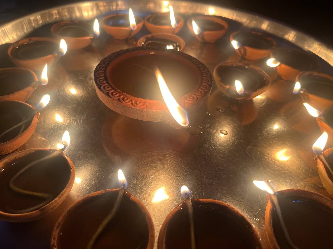 Clay oil lamps lit together on a brass tray